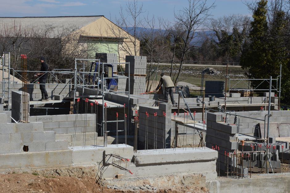 Construction workers building a concrete structure at a sunlit site.