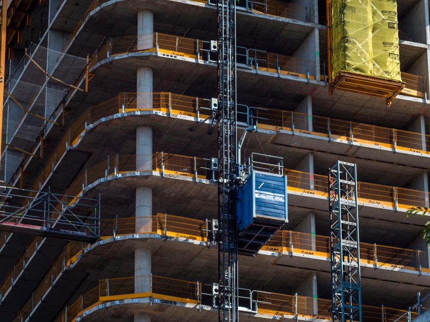 Detailed view of a high-rise building construction featuring a crane and multi-level scaffolding